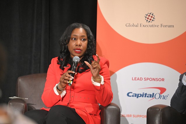 seated woman speaks into a microphone from a stage